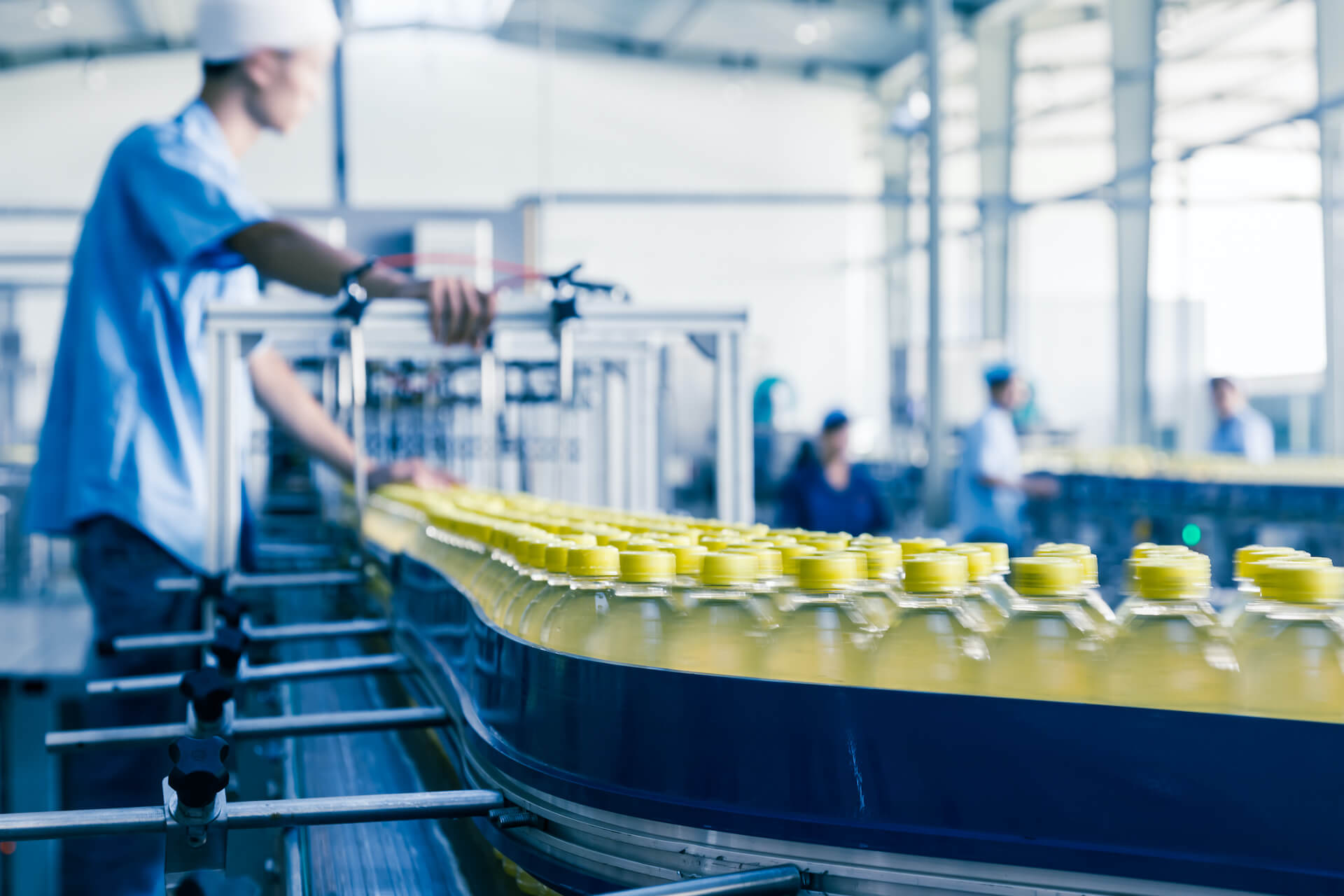Yellow-capped bottles on conveyor belt.