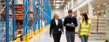 People walking through warehouse discussing logistics