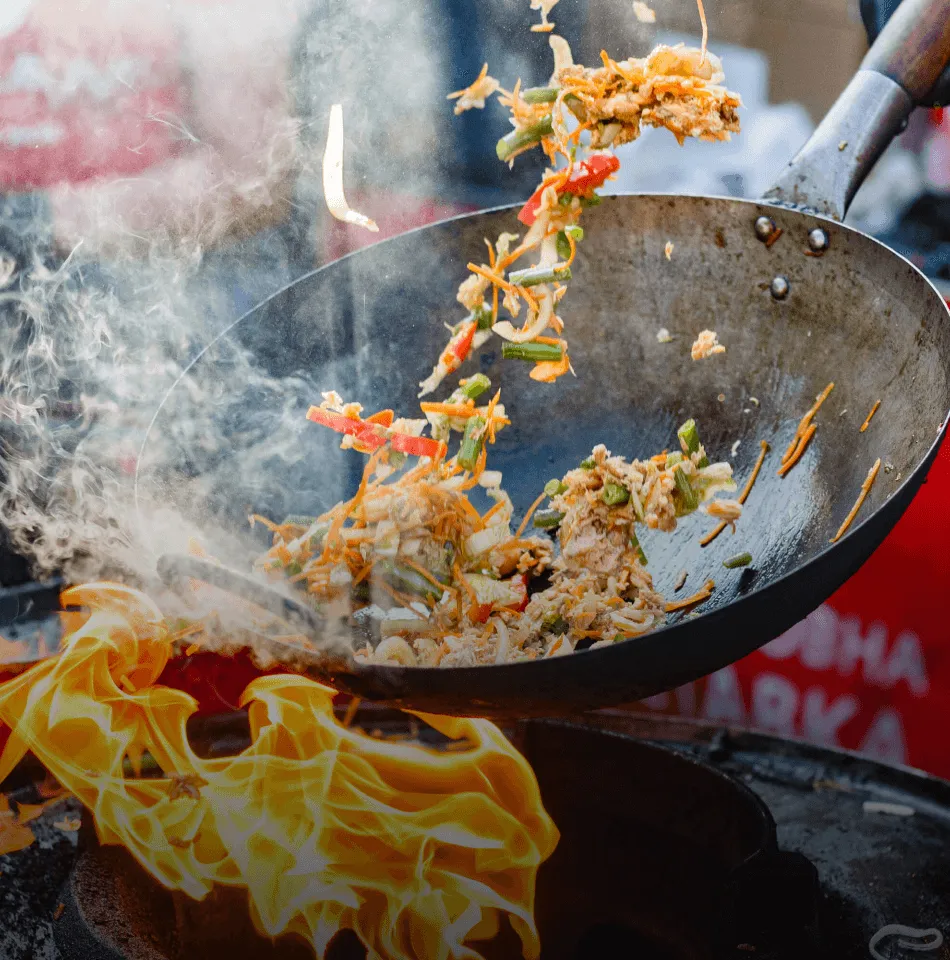 Food cooking in a wok over open flame